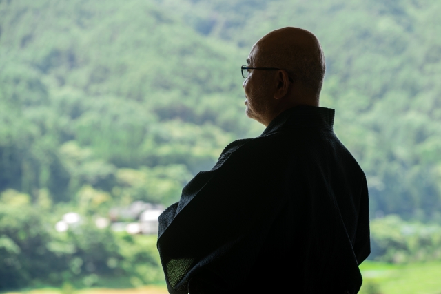 腕組みするシニア男性の後ろ姿