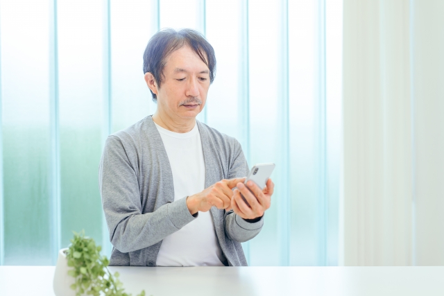 スマホをタップするシニア男性